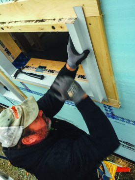 Above, a member of the metal roofing contractor's crew applies heavy bent metal trim over a window extension buck.