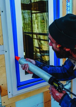 Above, David Kelly uses a commercial "sausage gun" to apply caulking to the gap between the metal trim and the flush-mounted window.