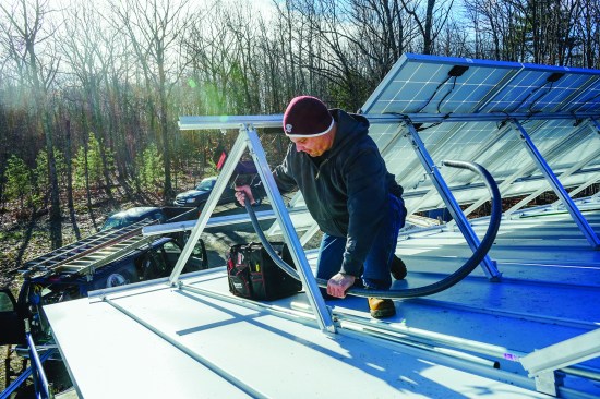 Above, electrician Joe Sewell installs conduit for solar panel wiring. Sewell oversaw the PV installation process and made the service panel and utility connections for the array.