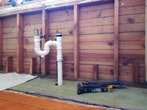 The original exit plumbing for the kitchen sink featured an S-trap and an air-admittance valve--both no nos in today's code. Removing the wall board and insulation to rerout the plumbing exposed these beautiful beaded pine sheathing boards original to the cottage from the 1940s.