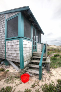 A colorful tub filled with water at the bottom of the front steps lets folks rinse the beach sand from their feet before going inside.
