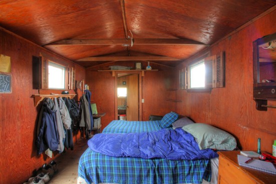 Two twin beds barely fit into this tiny room for sleeping. A door on the left is the back door of the shack.