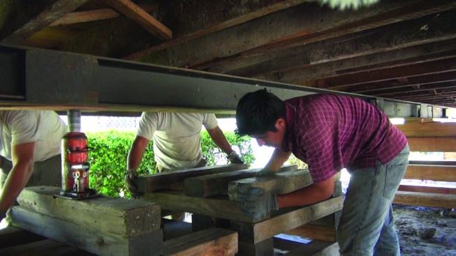 When the building is raised and oriented over its footing, he suspends the house on cribbing to allow reconstruction of the foundation and cripple wall.