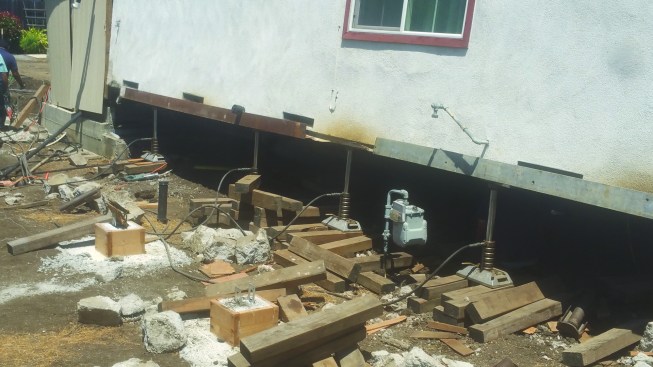 To lift a house after its cripple walls fail, Joy has to lever the building up one side at a time.