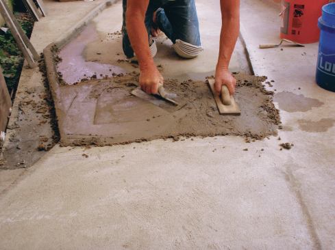 Using a wood float, compact the mortar to about 1/4 to 5/8 inch above the top of the screeds. Smooth it using a flat trowel.