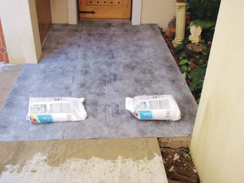 After dampening the mortar bed and aligning the sheet in place, weigh it down with a couple of bags of thinset to keep it from moving.