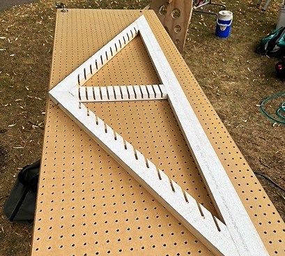By running the router along a slot in the jig, he cuts angled mortises across all three members of the frame.