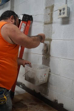 Toby  adds grout to the mortar joints to create a flat bonding surface.