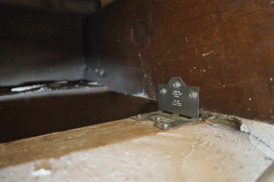 Part of the assessment required pulling  insulation out of the joist cavities to verify that the sill plate was anchored to the foundation wall. Bassed on what teh author's crew found, the engineer asked them to add angle brackets to reinforce the floor-joist-to-sill-plate connection.