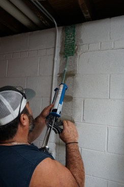 Toby applies epoxy to the wall in a close pattern.