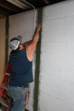 Toby applies a structural strap, pressing it firmly into the bed of epoxy
