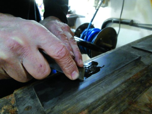 After grinding a 26° to 30° bevel on the iron, the author hones the edge on a whetstone to the same angle.