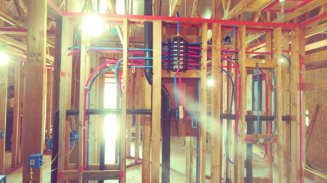 A view of the rough plumbing in a house under construction by the Habitat for Humanity affiliate in San Joaquin County, Calif. A short plumbing chase located in the double-wall partition between back-to-back bathrooms serves baths, toilets, and sinks in both bathrooms, as well as a kitchen sink at one end and a laundry at the other. Hot water is delivered to fixtures in seconds.