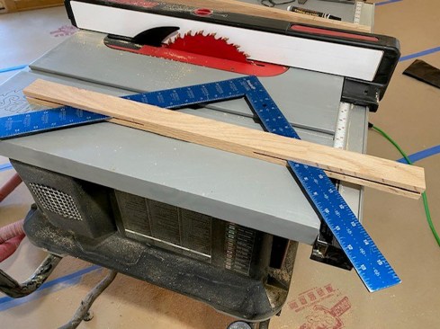 Instead of using stair gauges, the author makes a jig by ripping a kerf from each end of a 1x2. This can be lined up with the rise and run distances on the square, and the sides of the jig clamped with small C-clamps to hold the square in position while he steps off the stringer. 