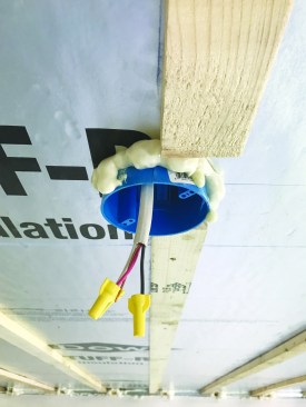 After strapping the ceiling in preparation for drywall, the author sealed all penetrations—including the electrical box for a ceiling fan—with canned foam sealant.