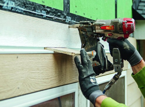 Without a housewrap to hide the nailing on studs, Huber’s Zip system makes it easy to nail siding into studs. Over window and door heads, the author uses a scrap piece of siding to keep an even 3/8-inch gap between the siding and Z-flashing.