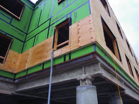 This view of the Elm Place building under construction shows the partially constructed wall with sealed Zip System sheathing and “half SIP” nailbase. The exposed steel and concrete floor structure seen here would later be enclosed with framing and insulation.