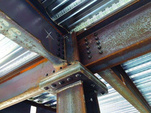 The thermally broken steel-plate connection supports steel girders under the galvanized pan for the structural slab. All of the steel floor frame and the concrete slab ended up inside the thermal envelope.