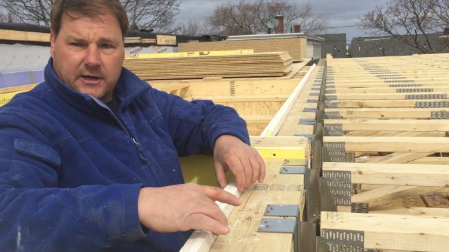 "There is no plate-to-plate wood connection anywhere in this building" between the fire-protected spaces, explains Rob Paisley. The truss hangers shown here provide a one-inch space that allows gypsum board to be slipped between the floor frame and the wall frame.