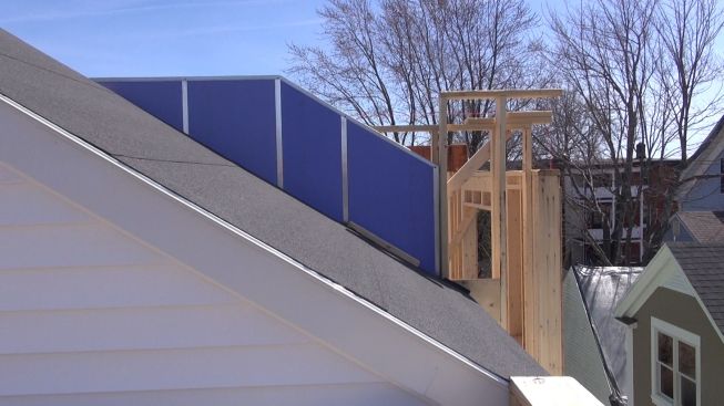 A view of the new firewall assembly over the rooftop of the neighboring building's roof access structure. The gypsum board is intended to protect either building from a fire in the neighboring structure.