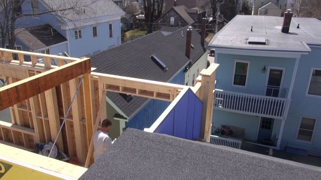 A view of the partially completed firewall as seen over the top of the neighboring building's rooftop access structure. The frewall is being assembled in stages as the new building goes up and provides the workers with a working platform.