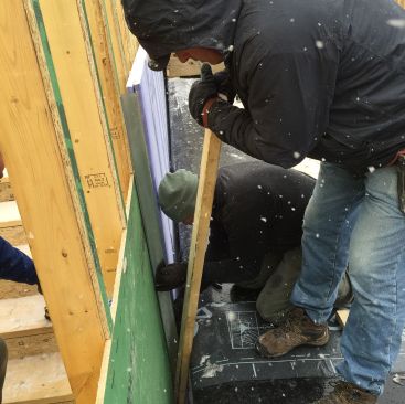 The crew slips an H-stud over the edge of the double layer of 1-inch gypsum board.