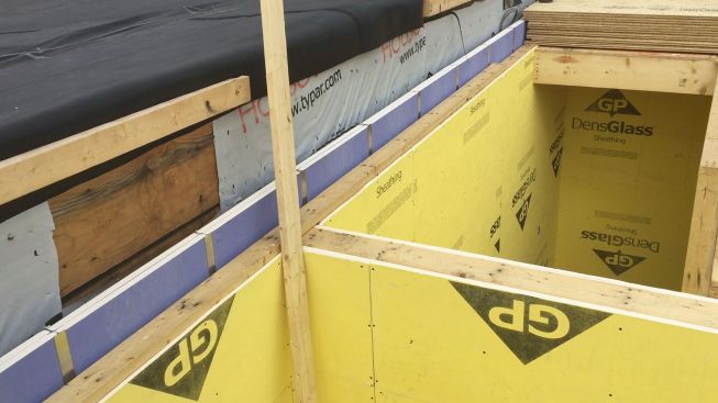 The yellow GP DensGlass gypsum board at right is protecting the walls of the two stairwells for the building, which also must be fire-rated assemblies. DensGlass was chosen for this assembly because of its weather resistance as well as its fire resistance, since the assembly must be left exposed to the weather for weeks during construction.
