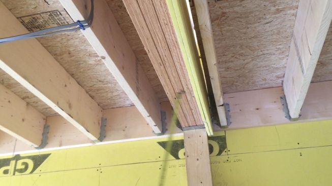 A view of the underside of a stairwell from the garage level. Gypsum board continues through the floor assembly to completely isolate the stairwell from the rest of the building. The DensGlass gypsum board extends down an inch to meet up with more DensGlass that will be applied to the ceiling. Each floor of the building will be isolated in this manner from the floors above and below.