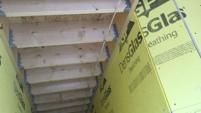 The ceiling of a hallway between the elevator shaft and the garage on the building's street level. Both walls are fire-protected. Like other floors in the building, the framing above is fastened through the DensGlass with structural screws. This ceiling will also receive one inch of gypsum board.
