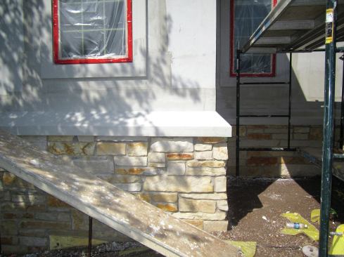 When the backer rod and caulk are installed around the windows, the sealant needs to adhere to the backwrapped edge of the preformed foam trim, but not to the finish coat, to prevent contraction of the sealant from causing the finish coat to separate from the base coat. The tape securing the poly that protects the windows gives a crisp edge to apply the sealant to, free of any finish topping.
