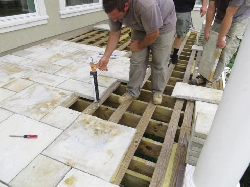 Paver installation goes quickly. Working from a CAD-generated pattern, workers apply landscaping stone adhesive to the sleepers.