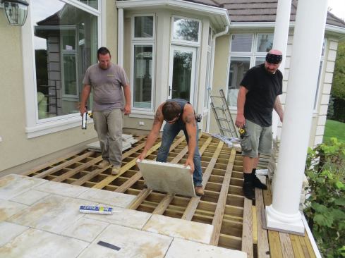 A worker places a paver, leaving a 1/4-inch gap between the ungrouted pavers for drainage.