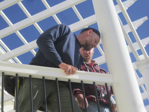 The vinyl pergola and rails were supplied by the same manufacturer; workers profiled the ends of the rail for a tight fit to the columns.