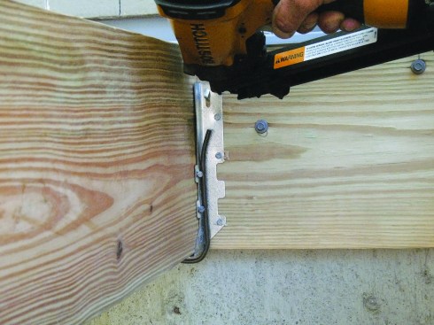 Figure 1. Install joist hangers tight to the wood. The Joist Clip, a simple spring wire clamp, eases the task and keeps fingers out of harm’s way.
