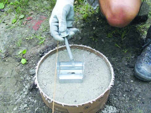 Figure 9. When the footings go in before the deck is framed, bolt-down post bases make precise post alignment a cinch. 