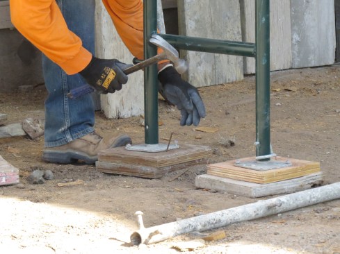 The installer is digging out the ground and placing an extra sill block to hold the plate against the frame.