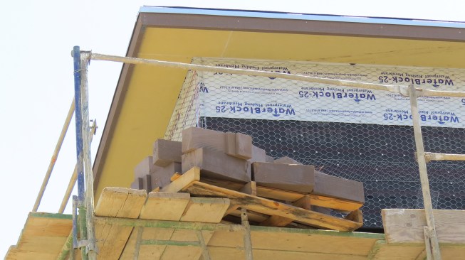 The danger posed by objects that could fall off the scaffold is real: In this example, workers loading a pallet of corbel trim blocks onto the scaffold have removed the mid-rail. This situation, which the superintendent corrected during his inspection, created multiple risks for workers using the work platform, as well as for workers passing beneath it.