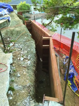 The existing concrete slab flanking the edge of the pool was demolished to expose the steel columns supporting the retaining wall. Blocks held the new 3x12 PT timber laggings in place until the excavation could be backfilled.