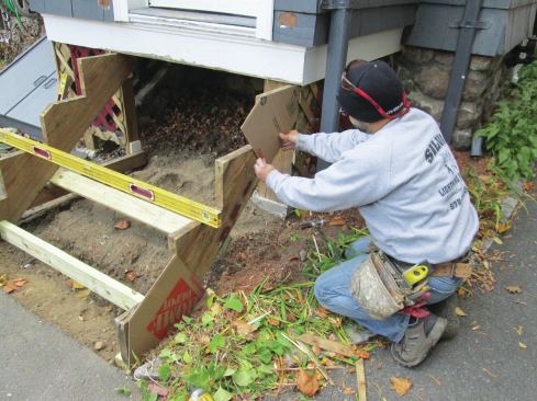 The author cut out two cardboard templates, one for each end of the stringer. Adding the distance between the templates to their lengths gave him the exact dimensions for the PVC skirtboards that would cover the stringers. 