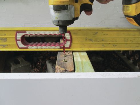 Each screw was adjusted until it was flush with the bottom edge of a level laid across the stringers. 