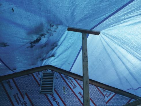 A temporary pole is used to hold up the tarp and channel water away from a potential trouble spot.