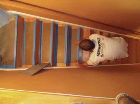 Tape rips of lauan onto wood stair treads using blue tape. Also cover banisters and newel posts.