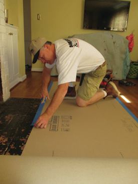A worker covers the floor with Ram Board, 46-mil-thick paper that comes in 38-inch-wide rolls.