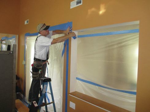 Plastic sheeting held in place with painter's tape seals off passageways and other openings, keeping dust contained.