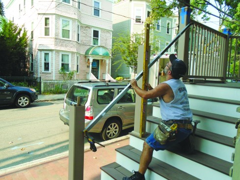 After verifying that the upper and lower stair posts are plumb, the author clamps them to a straightedge and repeats the procedure with the middle stair post.
