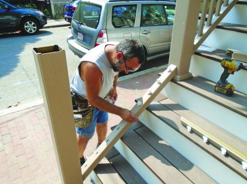 After cutting the bottom rail to length and snapping it over the support beam, the author installs the stair-rail plugs.