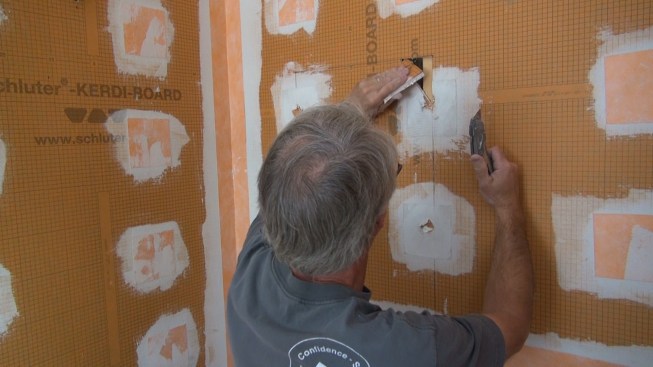 Boucher cuts a small triangular opening into the face of the wall where the box opening must be placed, to give himself a handhold on the piece of Kerdi-Board to be removed.