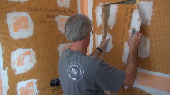 Boucher pulls the cut-out piece away from the wall.