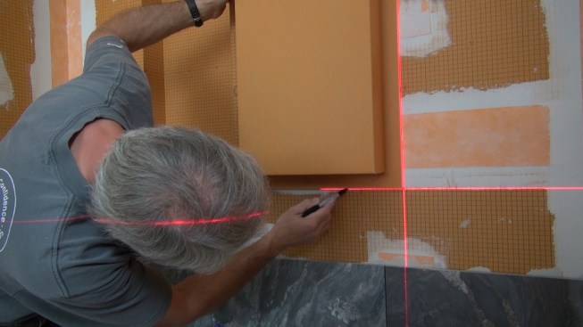 Boucher lays another recess box onto the wall next to the first one, and traces its outline onto the wall. He will now repeat the step of cutting out the opening.