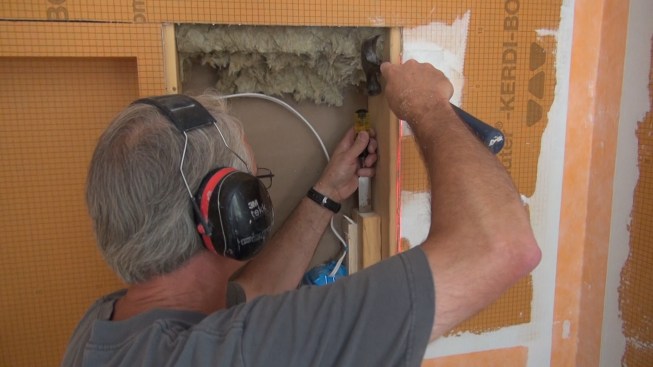 To make room for his shower recess box, Boucher has to chisel away a piece of the scabbed-on 2x4 that the electricians used to attach their wiring box.